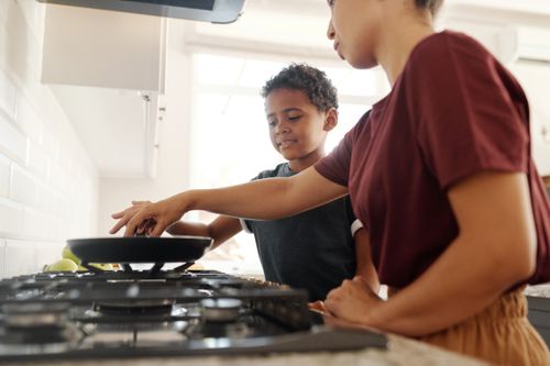 Free A mother and son share a bonding moment while cooking together in a bright kitchen. Stock Photo