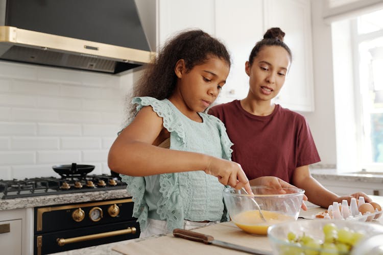 A Young Girl Mixing An Egg In A Bowl