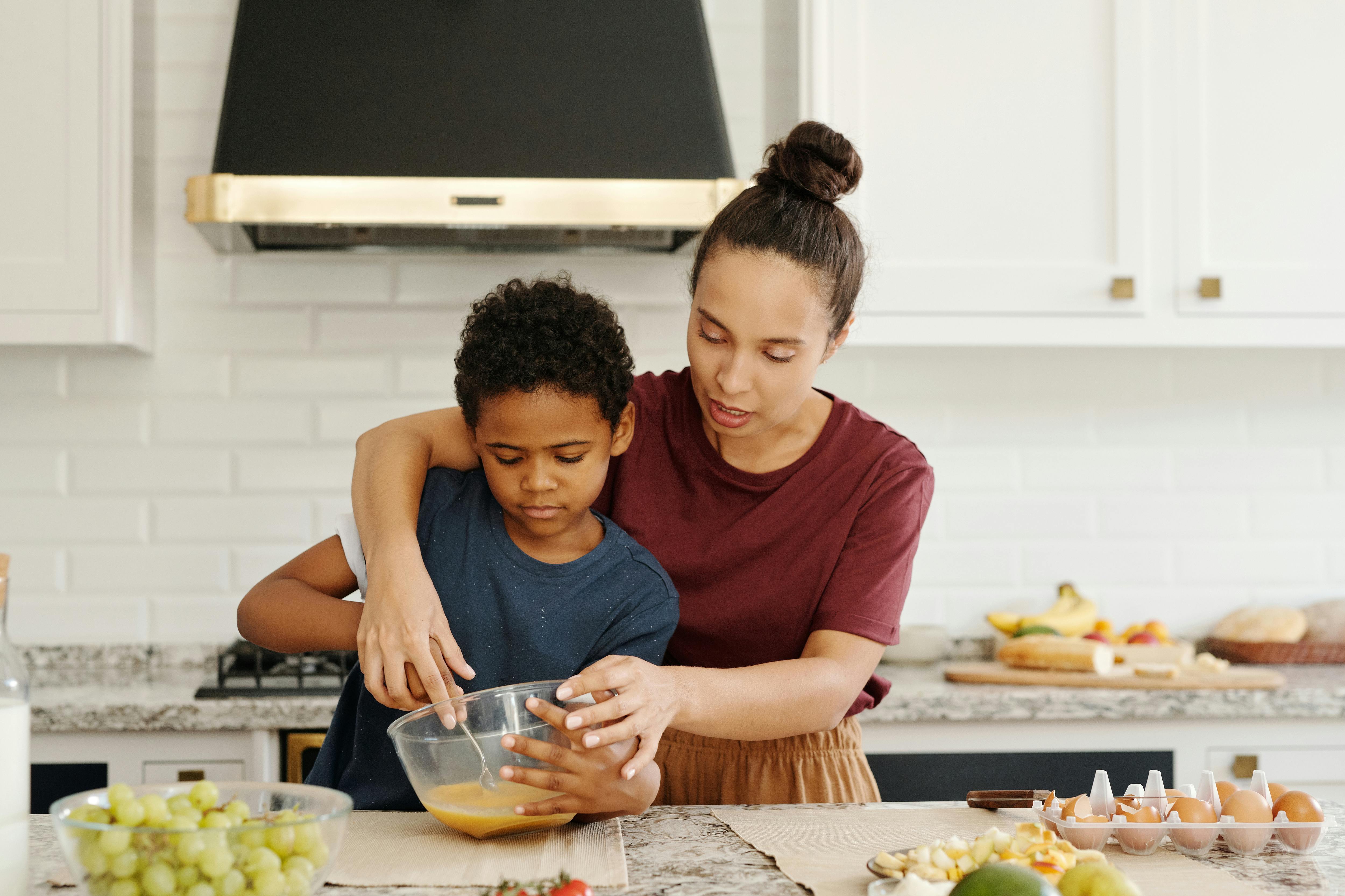 a woman teaching a young boy in cooking