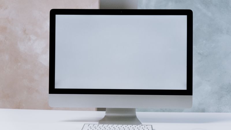 A sleek iMac desktop computer on a minimalist white desk with a keyboard and mouse.