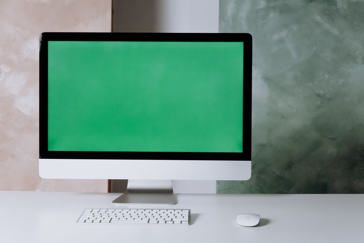 clean and minimalist setup with a computer and green screen on a white