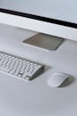 白色桌子上配备着键盘、鼠标和显示器，构成了极简主义的计算机设置
