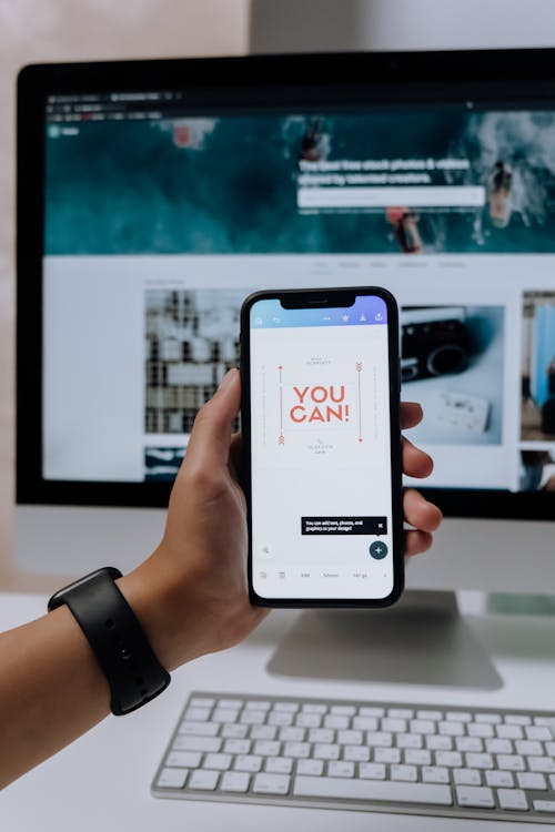 Free Holding a Smartphone in front of an Imac Stock Photo