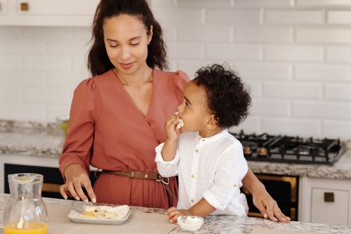 Free A mother and child enjoying snack time together in a modern kitchen setting. Stock Photo