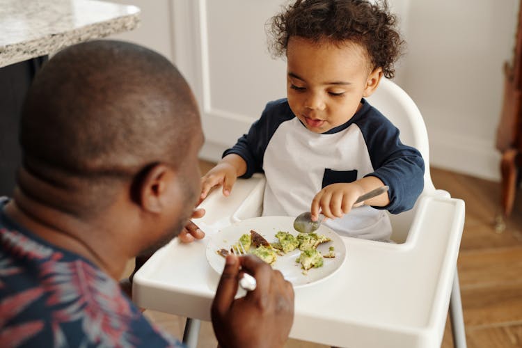 A Young Boy Eating White Sitting On White High Chair