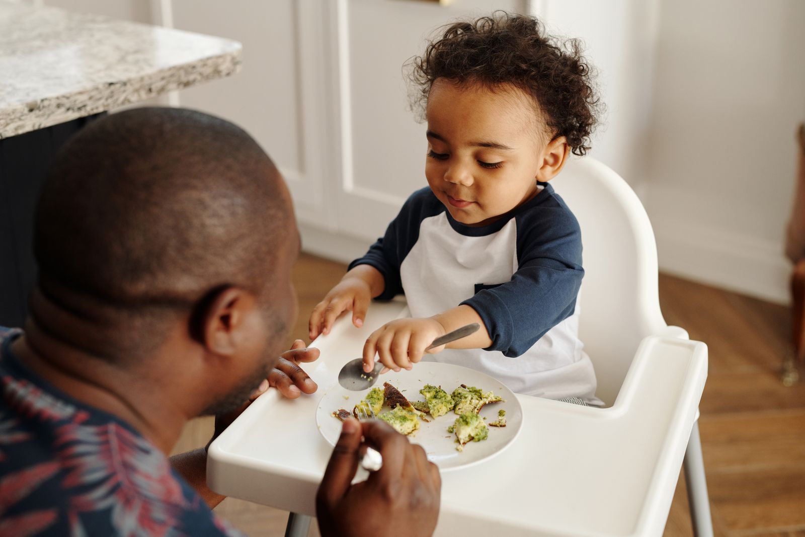 Man feeding a baby in a feeding chair, paediatric feeding therapy