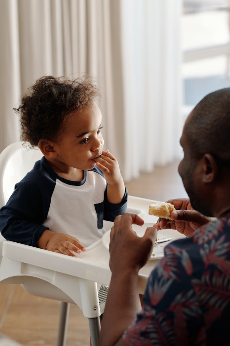 Man Feeding Baby In Feeding Chair