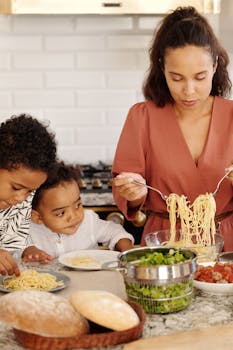 A mother prepares pasta with her children in a modern kitchen, creating a warm family moment indoors.