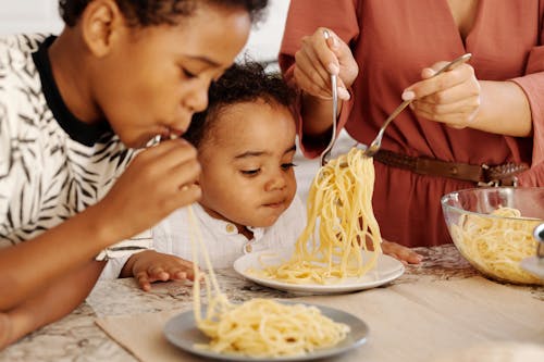A Young Boys Eating Pasta Together