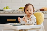 在舒适的厨房里，可爱的幼儿坐在高脚椅上享用美食和饮料