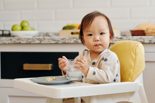 在舒适的厨房里，可爱的幼儿坐在高脚椅上享用美食和饮料