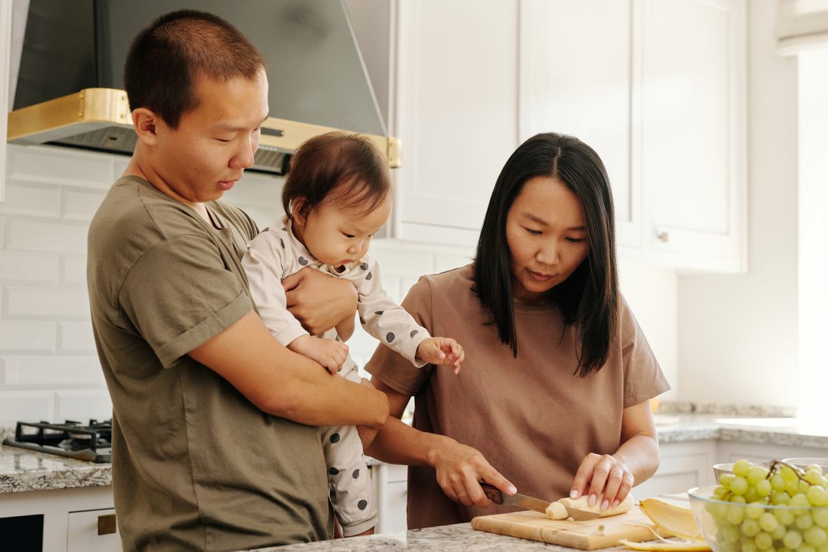 Família preparando alimentos saudáveis com uma criança na cozinha