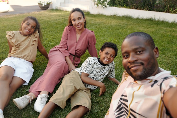 A Family Sitting On Grass For A Groupie Photo