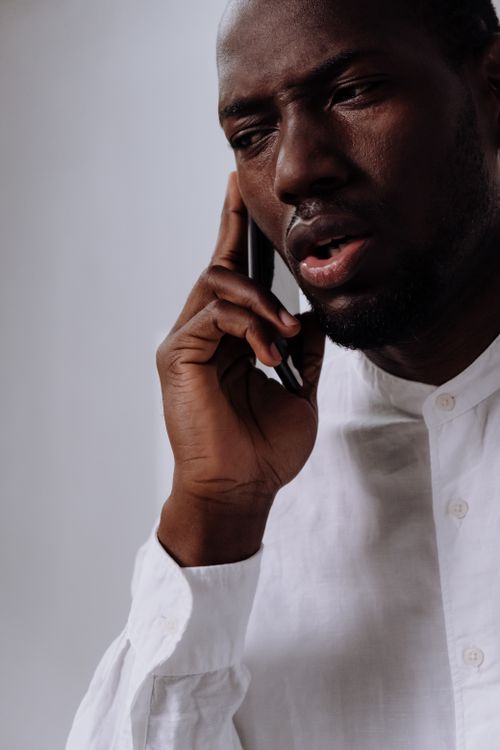 Man in a white shirt on a phone call with a concerned look, the kind of caller every answering option must serve well