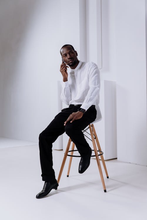 Free Man in White Dress Shirt and Black Pants Sitting on Brown Wooden Seat Stock Photo