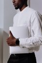 一位穿着白衬衫的职业男士在室内拿着笔记本电脑，展现了现代科技与商业风格