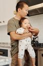 父亲在现代化的厨房里慈爱地抱着婴儿，展现了家庭的纽带