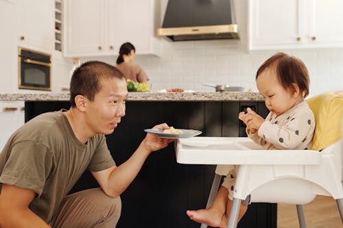 Free A Father Feeding a Toddler on a High Chair Stock Photo
