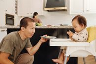 在时尚的厨房里，一位父亲正深情地喂养他的孩子，展现出家庭的关怀与亲密
