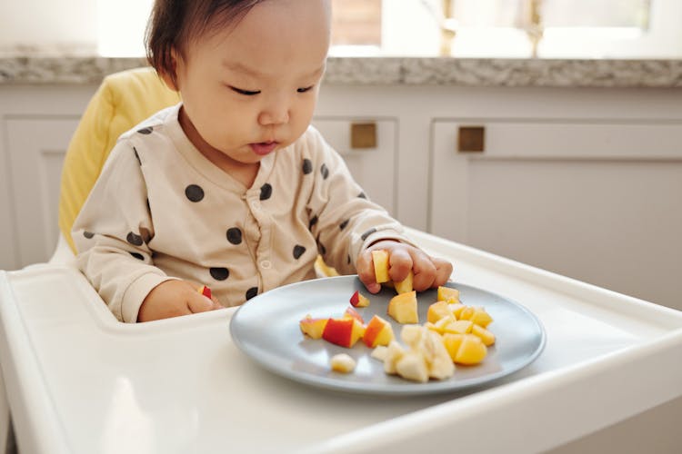  Baby On A High Chair Eating Fresh Fruits