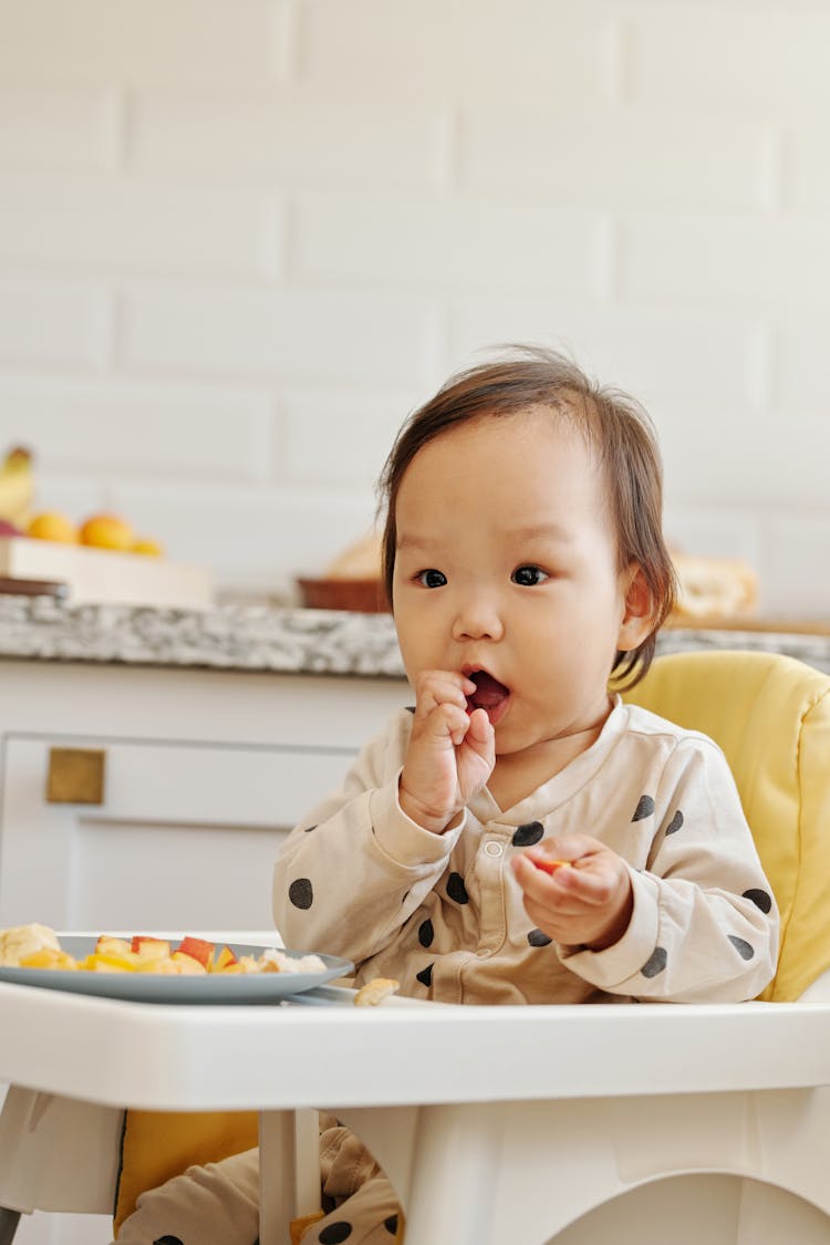 A Toddler Sitting N A High Chair Eating