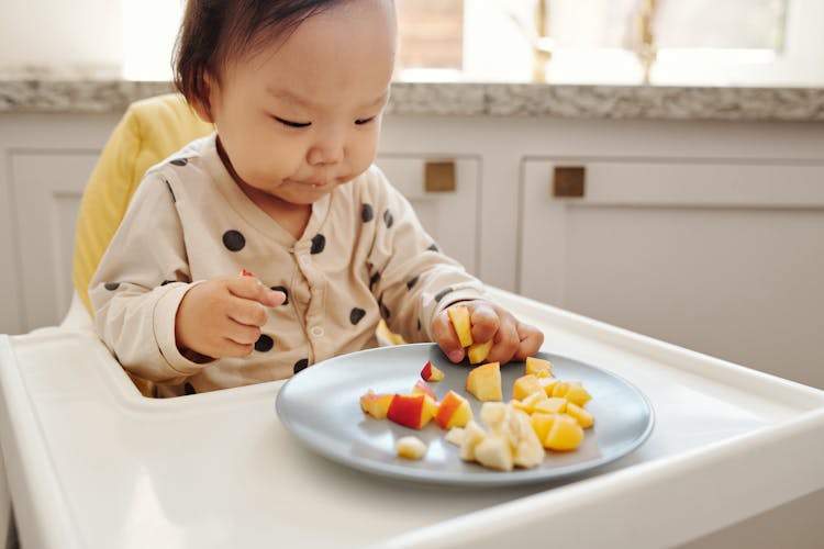 A Child Eating Fruits On A Plate