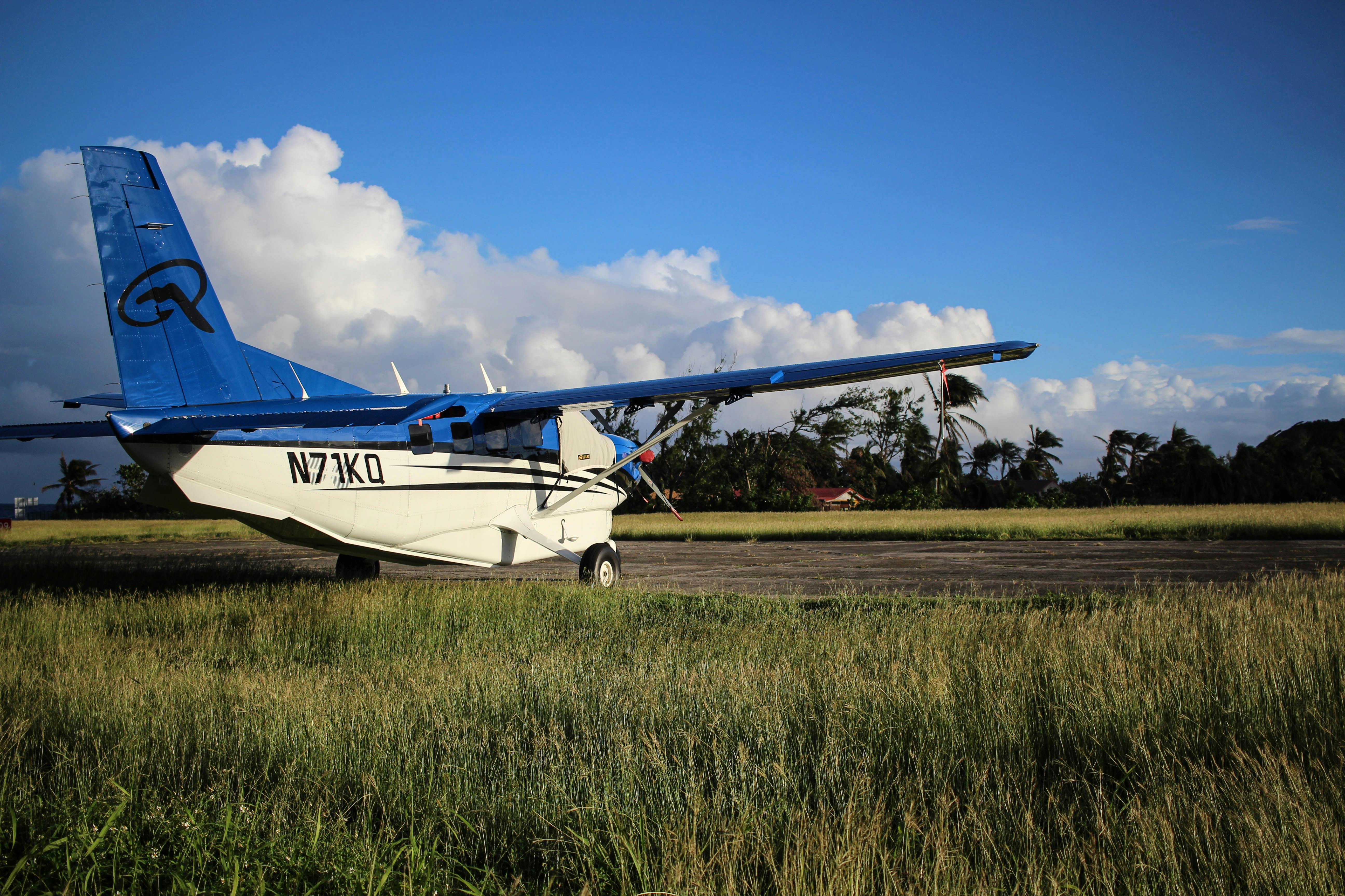 A small aircraft parked on a grassy runway under a blue sky in Guadeloupe.