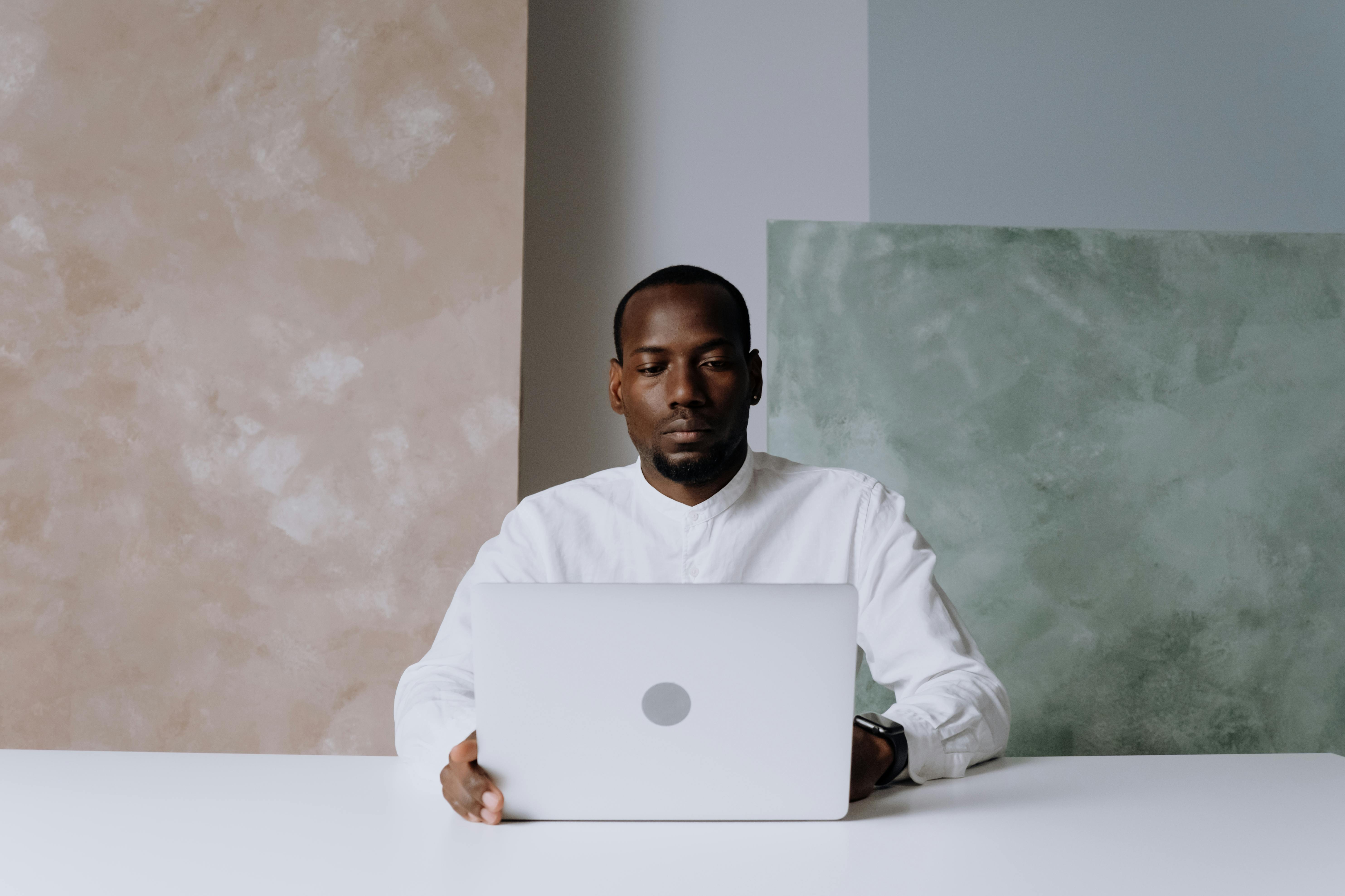 man in white long sleeve shirt using silver macbook