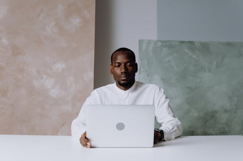 Man in White Long Sleeve Shirt Using Silver Macbook