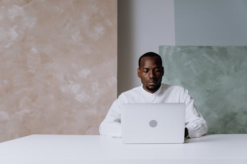 Man in White Crew Neck T-shirt Using Silver Macbook