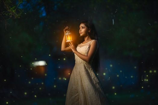一名身穿白色连衣裙的女子手持发光灯笼，营造出神奇的夜晚氛围