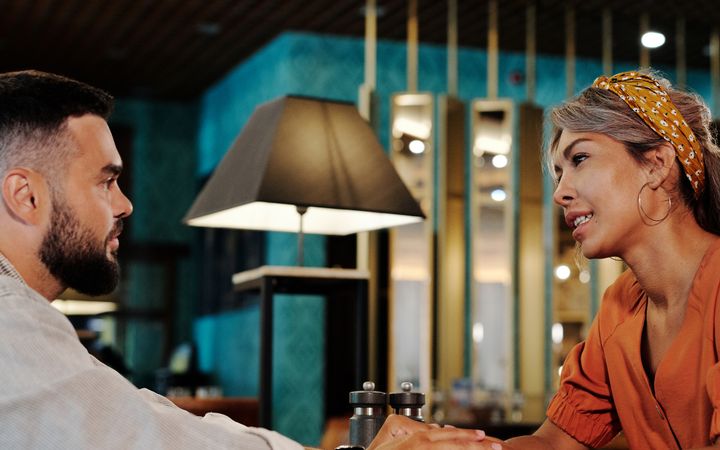 A couple enjoys a romantic date in a stylish indoor restaurant setting, chatting and connecting.