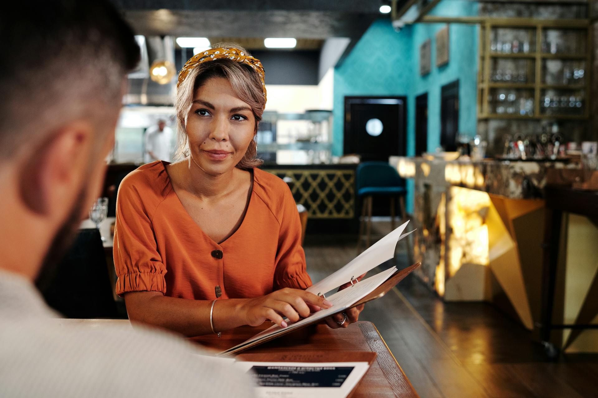 A couple enjoying a relaxed conversation while choosing from the menu in a modern café setting.