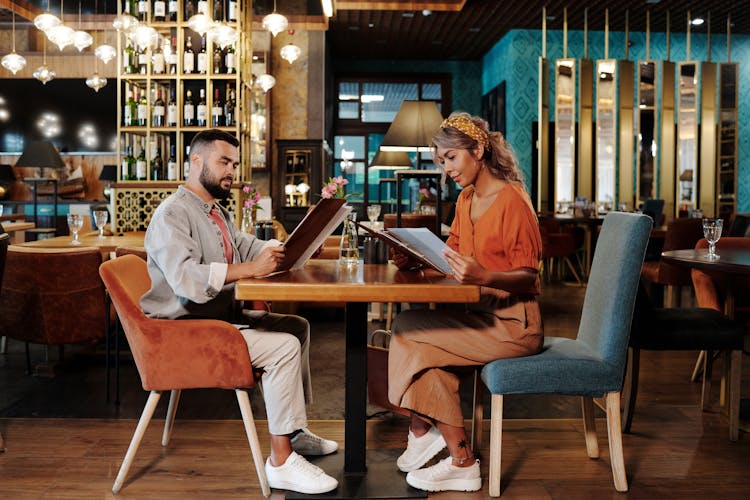 A Couple On A Date Looking At The Restaurant Menu