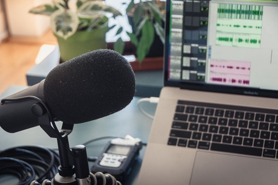Black microphone beside a laptop, set up for a podcast