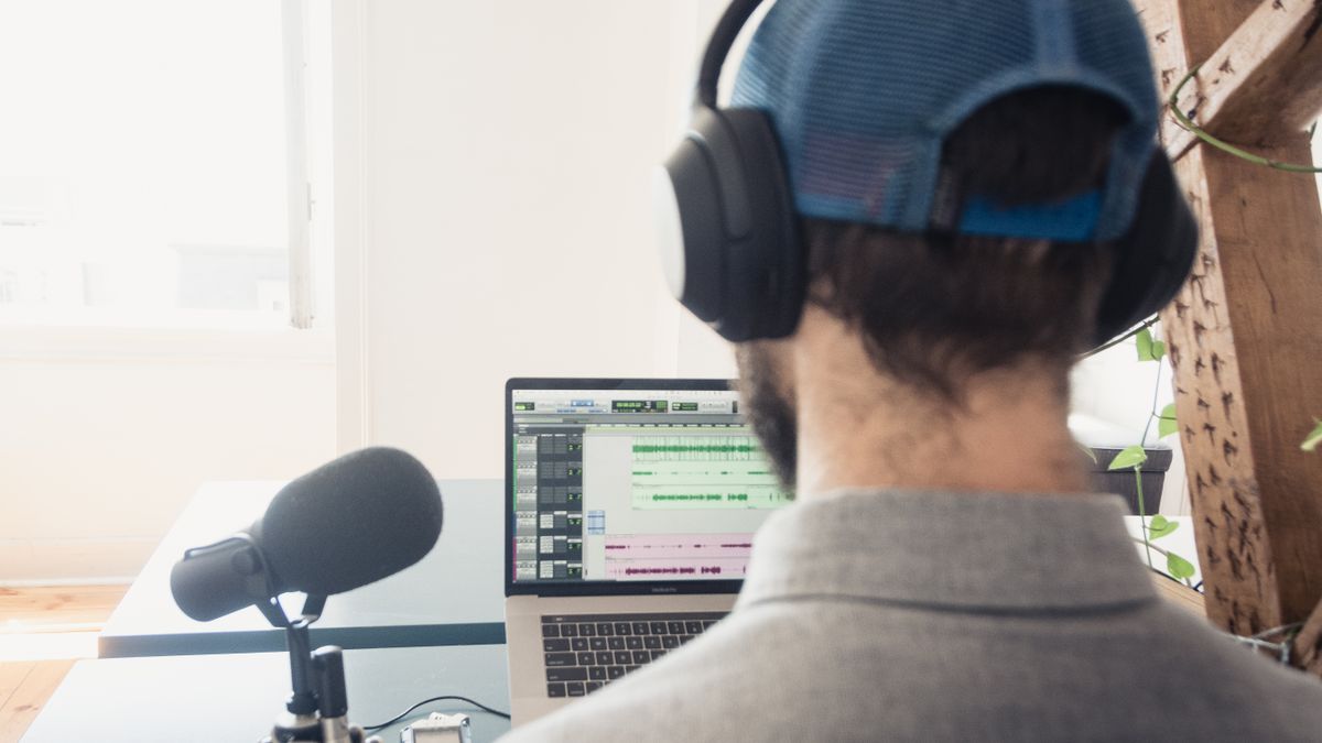 Audio creator working with headphones and digital production equipment