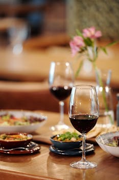 Close-up of a table setting with red wine and gourmet dishes, creating an elegant dining atmosphere.