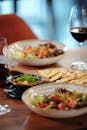Vegetable Salad on White Ceramic Bowl Beside Wine Glasses on Wooden Surface