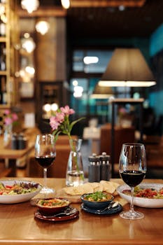 An inviting restaurant table setting featuring ceramic bowls, red wine, and ambient lighting.