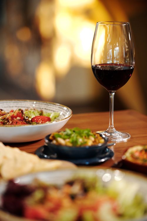 Free A glass of red wine paired with gourmet dishes in a cozy restaurant setting, perfect for a romantic dinner. Stock Photo