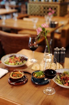 Fine dining table with diverse dishes and red wine in an elegant restaurant.