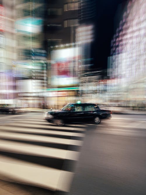 Cars driving on crossroad near illuminated skyscrapers in downtown of modern city at night