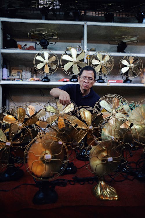 Free Ethnic old man selling golden fans in shop Stock Photo