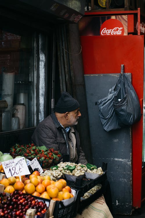 Elderly ethnic man selling fruits on street market