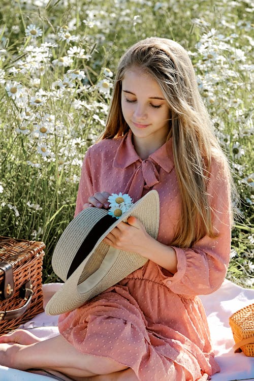 Free Thoughtful young woman surrounded by daisies in field Stock Photo