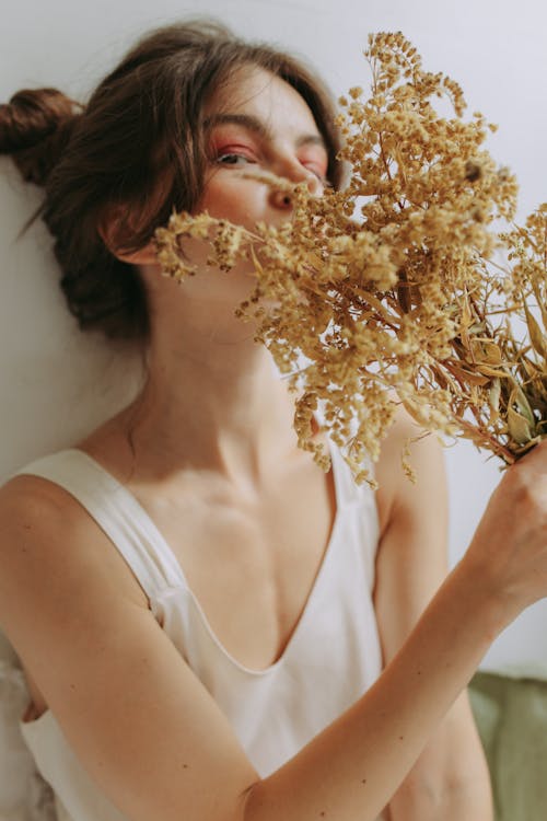 A Woman in White Tank Top Holding Withered Flowers