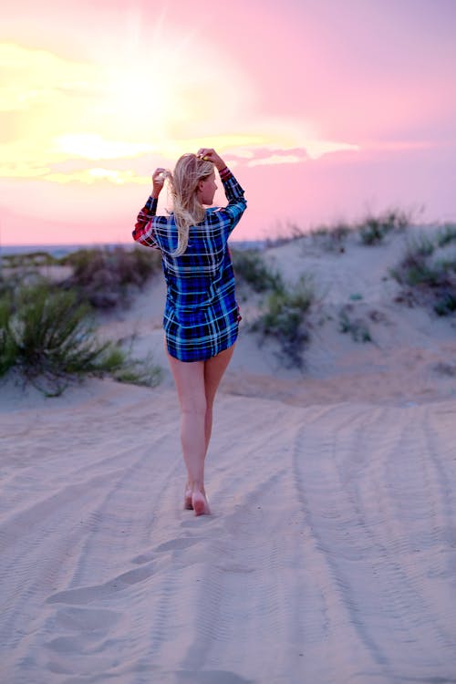 Alluring woman standing on sandy dunes in sunset light