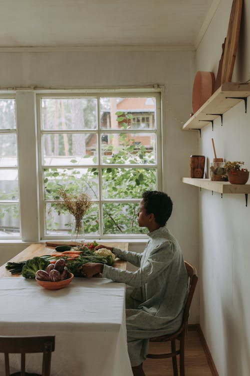 A Woman Sitting on a Dining Area with Vegetables