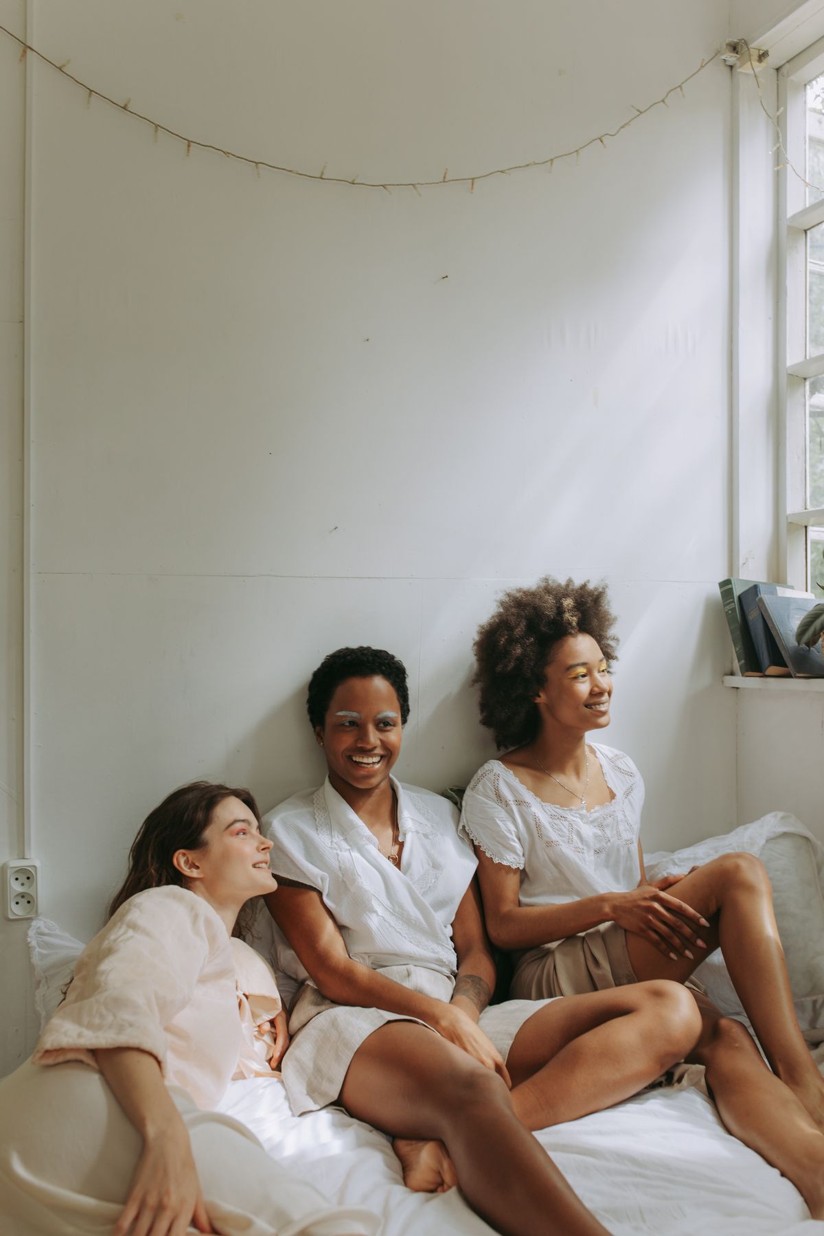 Three friends sitting together indoors, smiling and talking, party games for adults without alcohol