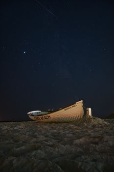 沙滩上，船的夜间景色非常迷人，繁星满天的景象很适合占星学和天文学主题